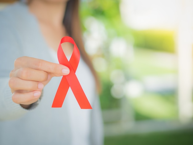 Woman hand holding red ribbon HIV, world AIDS day awareness ribbon