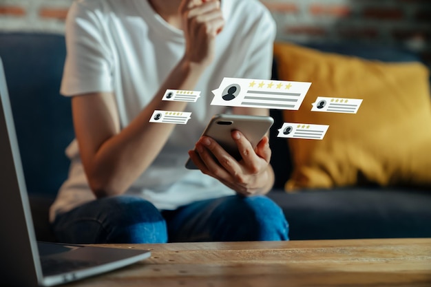 写真 スマートフォンを持っている女性の手とあなたのフィードバックを評価し、アプリケーションで5つ星を表示します。