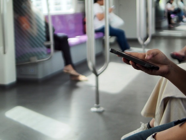 Foto una donna che tiene la mano usando uno smartphone sul treno