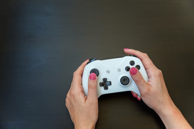 Woman hand holding white joystick gamepad, game console isolated on black background