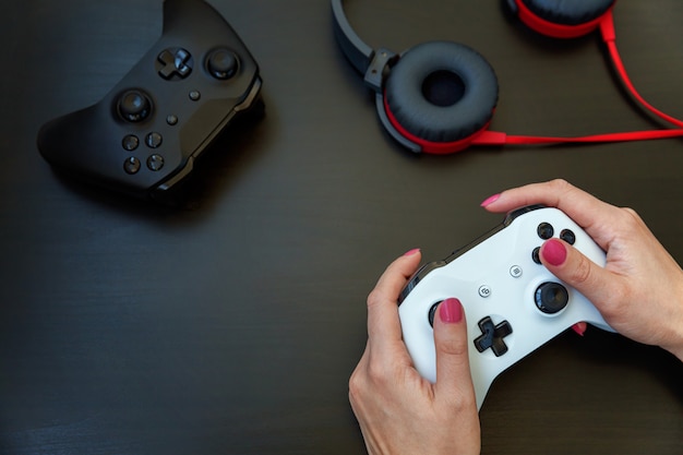 Woman hand holding white joystick gamepad, game console isolated on black . 