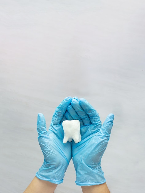 Woman hand holding white tooth on pastel blue background Dentist stomatology medical concept