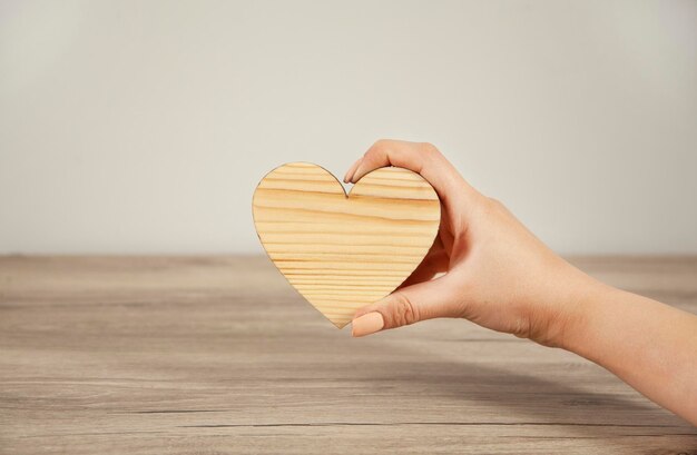 Woman hand holding wooden heart