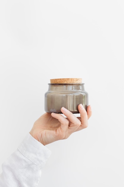 Woman hand holds closed lid scented candle in glass jar  Wellness concept