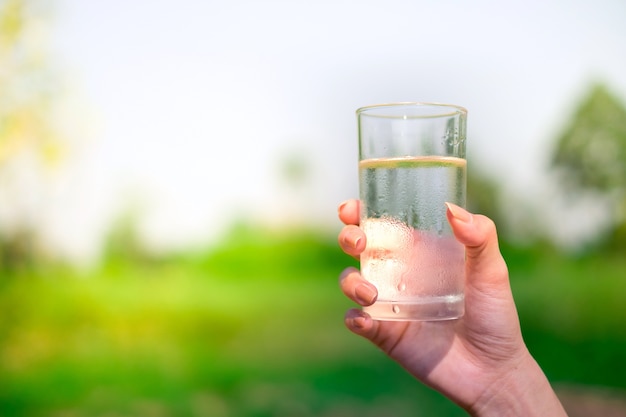 Woman hand holds a glass of cold water 