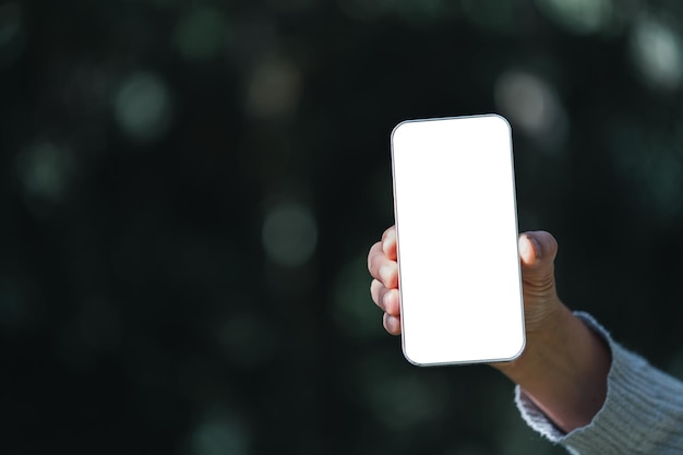 Woman hand holds modern white screen smartphone on floral background Travel concept Business office ideas Choice of travel Copy space Online store technology digital cyberspace web network