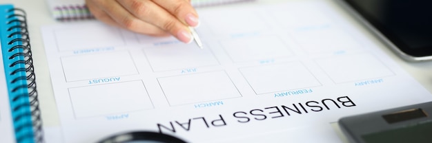 Woman hand holds pen and analyzes business plan