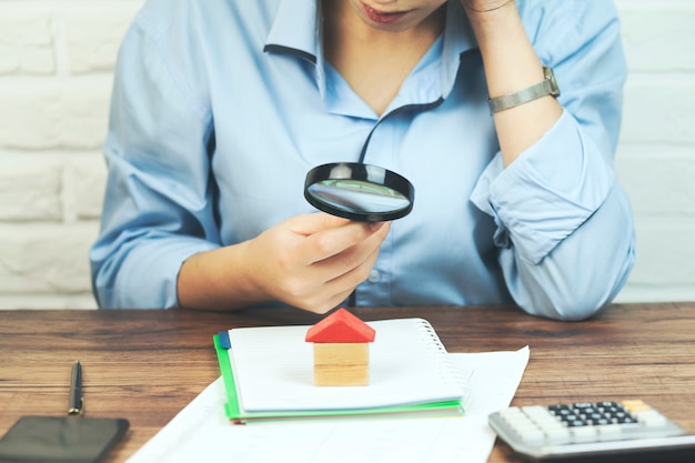 Woman hand house model and magnifier