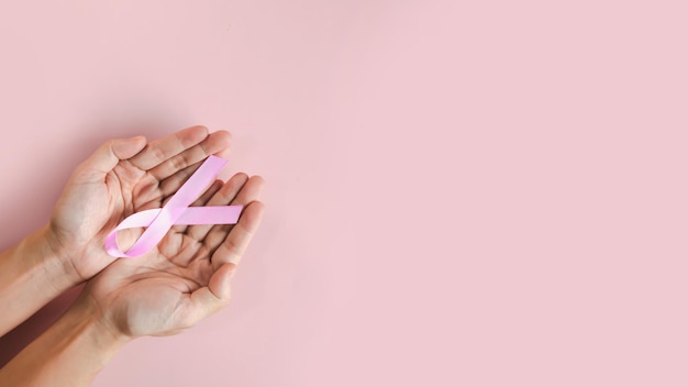 Foto la mano della donna tiene in mano un fiocco rosa per incoraggiare i malati di cancro al seno e sostenere la campagna contro il cancro al seno nel mese di ottobre