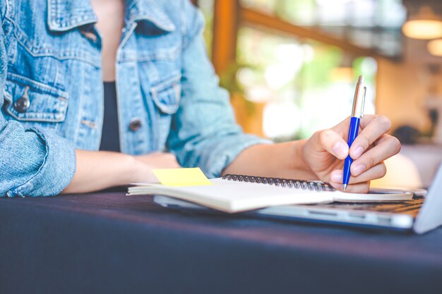 Woman hand is writing on a note pad with a pen in the office.