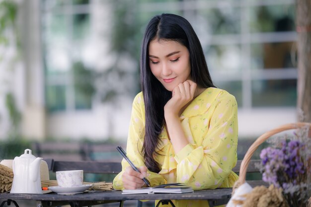 woman hand is writing on notepad with a pen in the garden