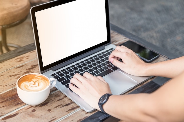 woman hand on laptop with mobile phone and coffee