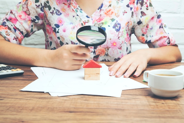 Photo woman hand magnifier and house model