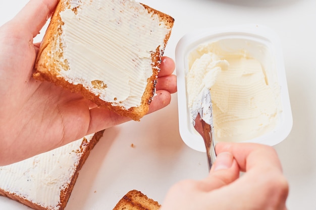 Woman hand make sandwich, spred toasted bread with a cheese