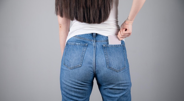 Woman hand mobile phone in the back pocket