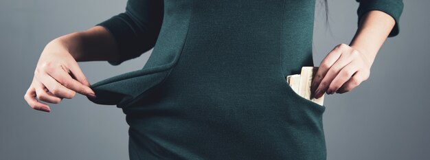 Woman hand money on pocket on grey background