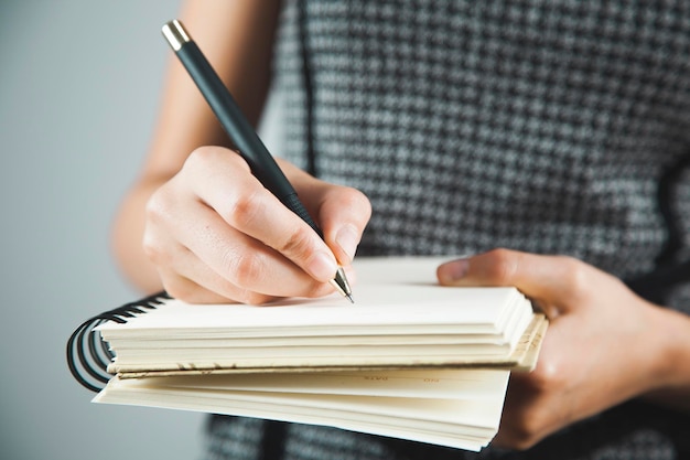 Blocco note e penna della mano della donna