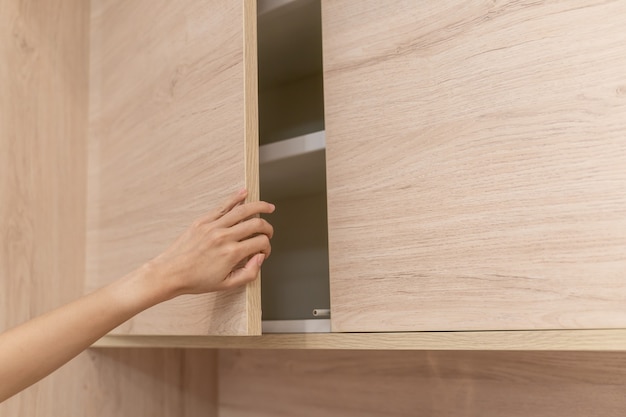 Woman hand open wooden cupboard doors.