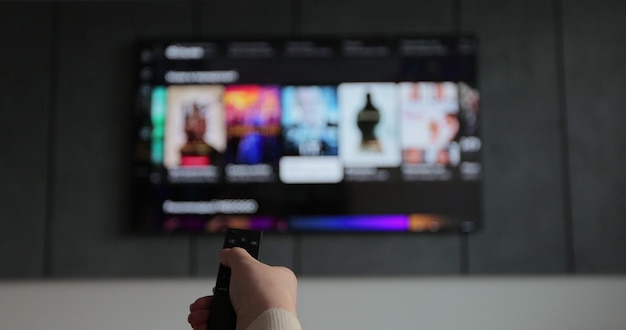 Foto la mano della donna che gestisce un telecomando per un canale di tv intelligente si concentra sulla mano e sul telecomando