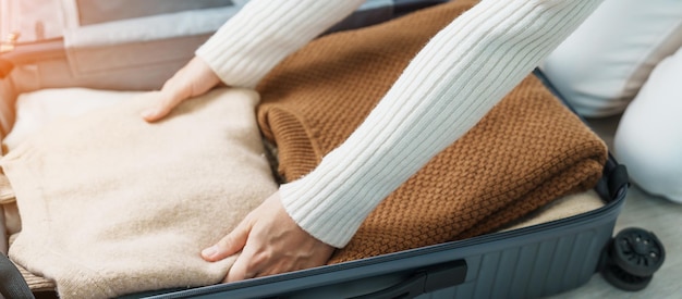 Женщина вручную упаковывает свою зимнюю одежду в багаж. Время путешествовать. Расслабьтесь весной, осенью или зимой.