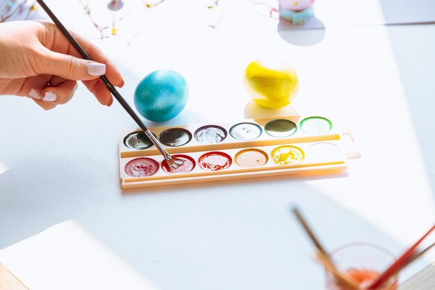 Photo woman hand paint easter egg with watercolors preparation for egg hunt game