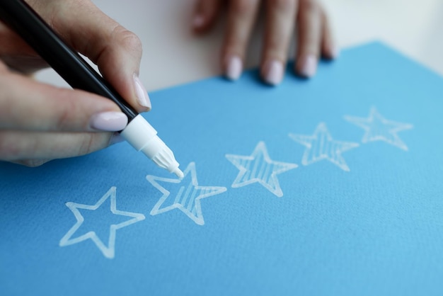 仕事のクローズアップを評価するための青い紙の上の星の上の女性の手塗り