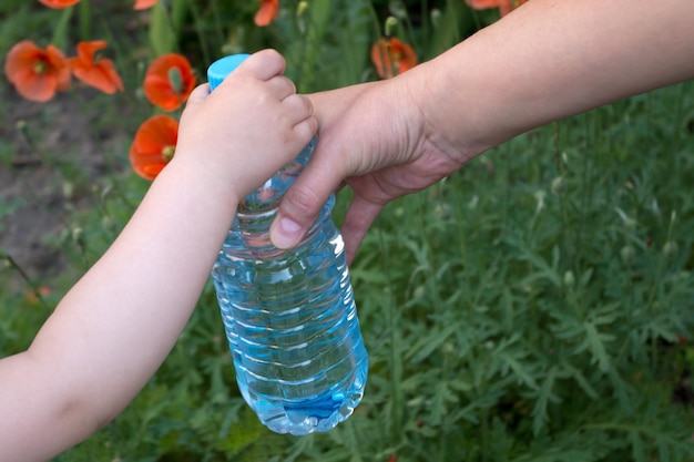 写真 女性の手は小さな子供の手に水とペットボトルを渡します