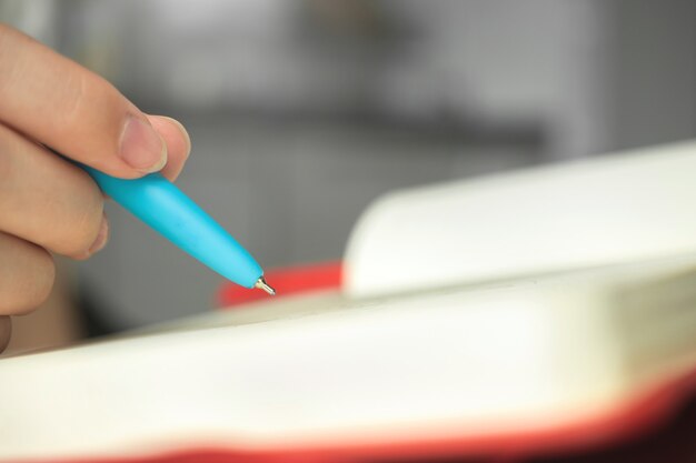 Woman hand and pen with notebook close-up, young artist writing, concept photo of hobby or design working