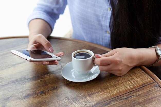 Woman hand phone and coffee in cafe