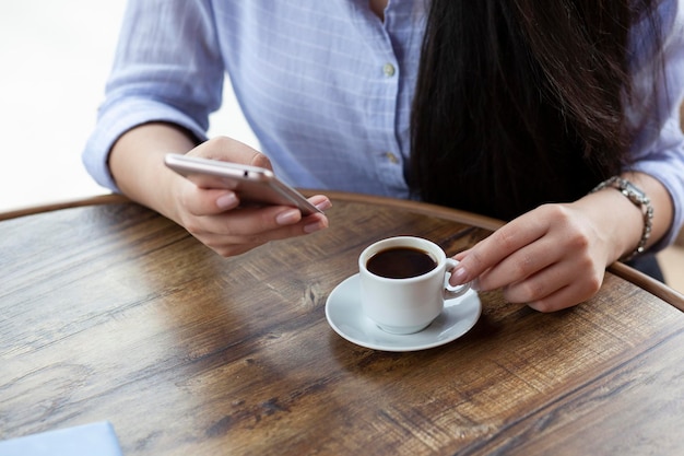 女性の手の電話とコーヒー