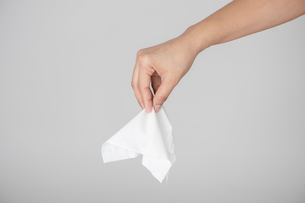 Woman hand picking white tissue paper from tissue box on gray . Healthcare and hygiene . 