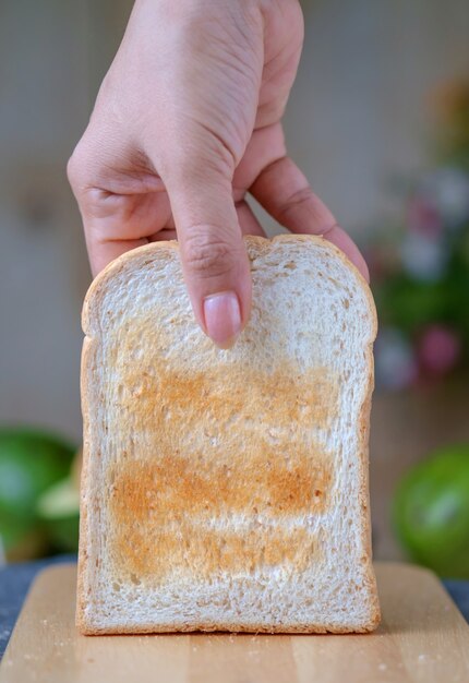 Woman hand picks a toasted bread for wooden table