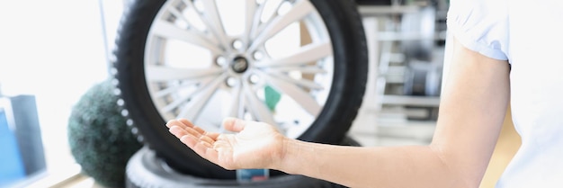 Photo woman hand pointing to wheels of car in repair shop closeup. tire auto service concept