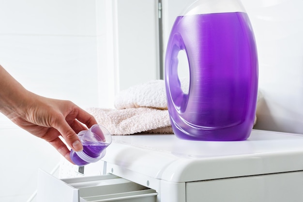 Woman hand pouring liquid detergent in the washing machine