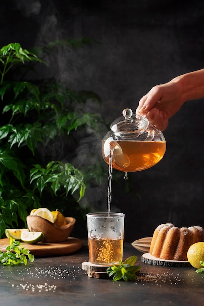 Woman hand pourung a hot black tea on the black background, selective focus image