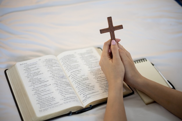 Mano della donna che prega sulla sacra bibbia al mattino. studia la bibbia con il culto online.