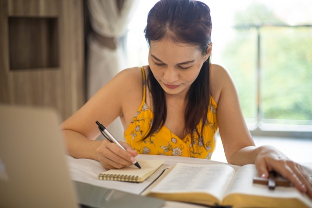 Woman hand praying on holy bible in the morning. Study bible with online worship.