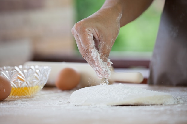 Photo woman hand preparing bread dough sprinkling