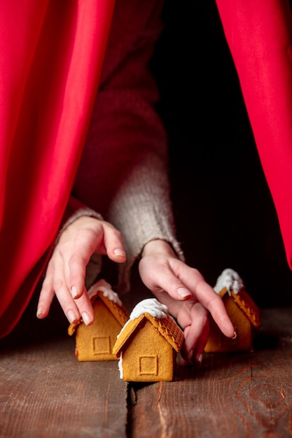 Woman hand present Christmas gingerbread house on wooden table