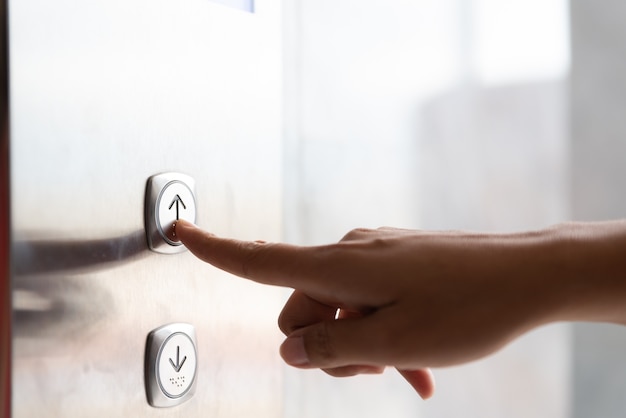 Donna mano premere un pulsante su di ascensore all'interno dell'edificio