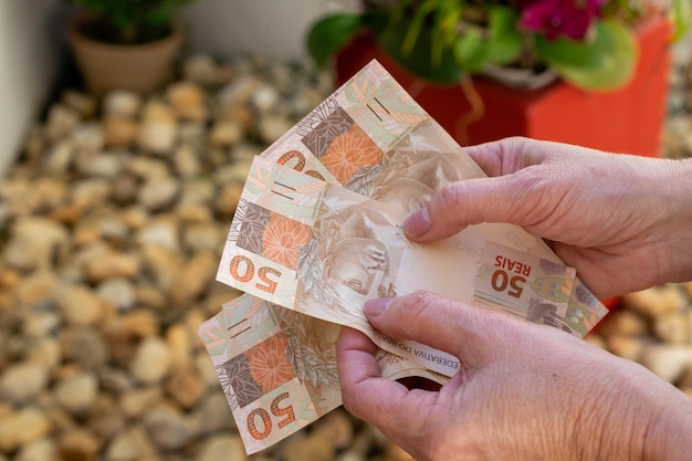 Woman hand providing Brazilian money banknotes