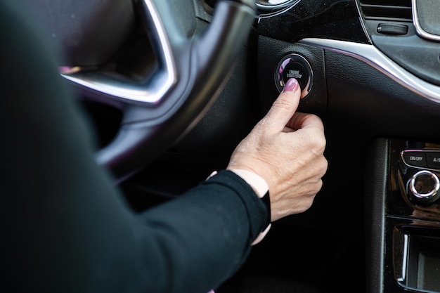 Woman hand pushing on car engine startstop button Modern car interior closeup