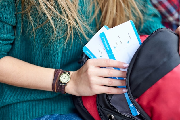 Фото Рука женщины положила посадочный талон в сумку. рука держит билеты. в ожидании самолета и путешествия