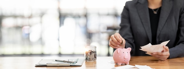 woman hand putting money coin into piggy bank for saving money wealth and financial concept panoramic background