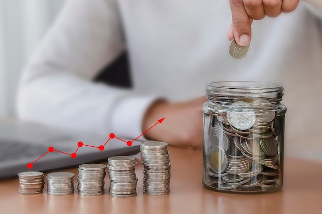 Woman hand putting money coin into piggy for saving money wealth and financial concept