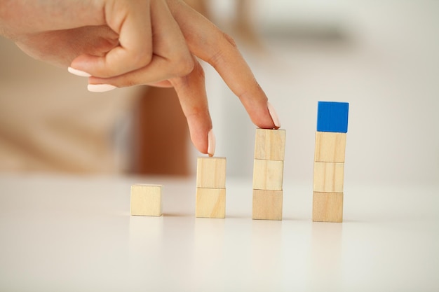 Woman hand putting and stacking blank wooden cubes on desk with copy space for input words