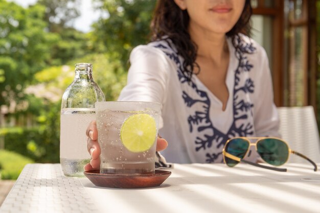 女性の手は、炭酸水の健康的な栄養のガラスに到達します。