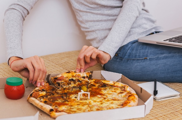 Woman hand scoop up and slice of hot pizza with melting cheese 