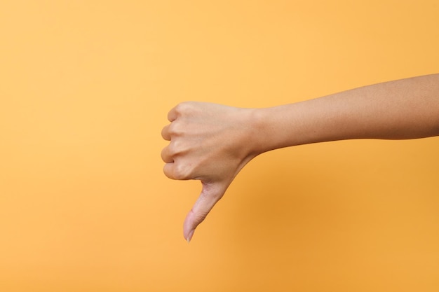 노란색 배경에 엄지손가락을 보여주는 여성 손 부정적인 감정, 감정 및 표시