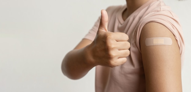 Woman hand showing thumbs up has gone to vaccinate coronavirus covid19 shoulder with a bandage